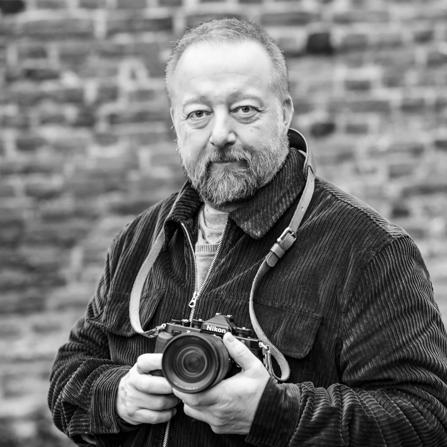 Portrait de Vincent Salmon, photographe liégeois, devant un mur de briques